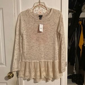 A long sleeve top with lace and floral decoration at the bottom